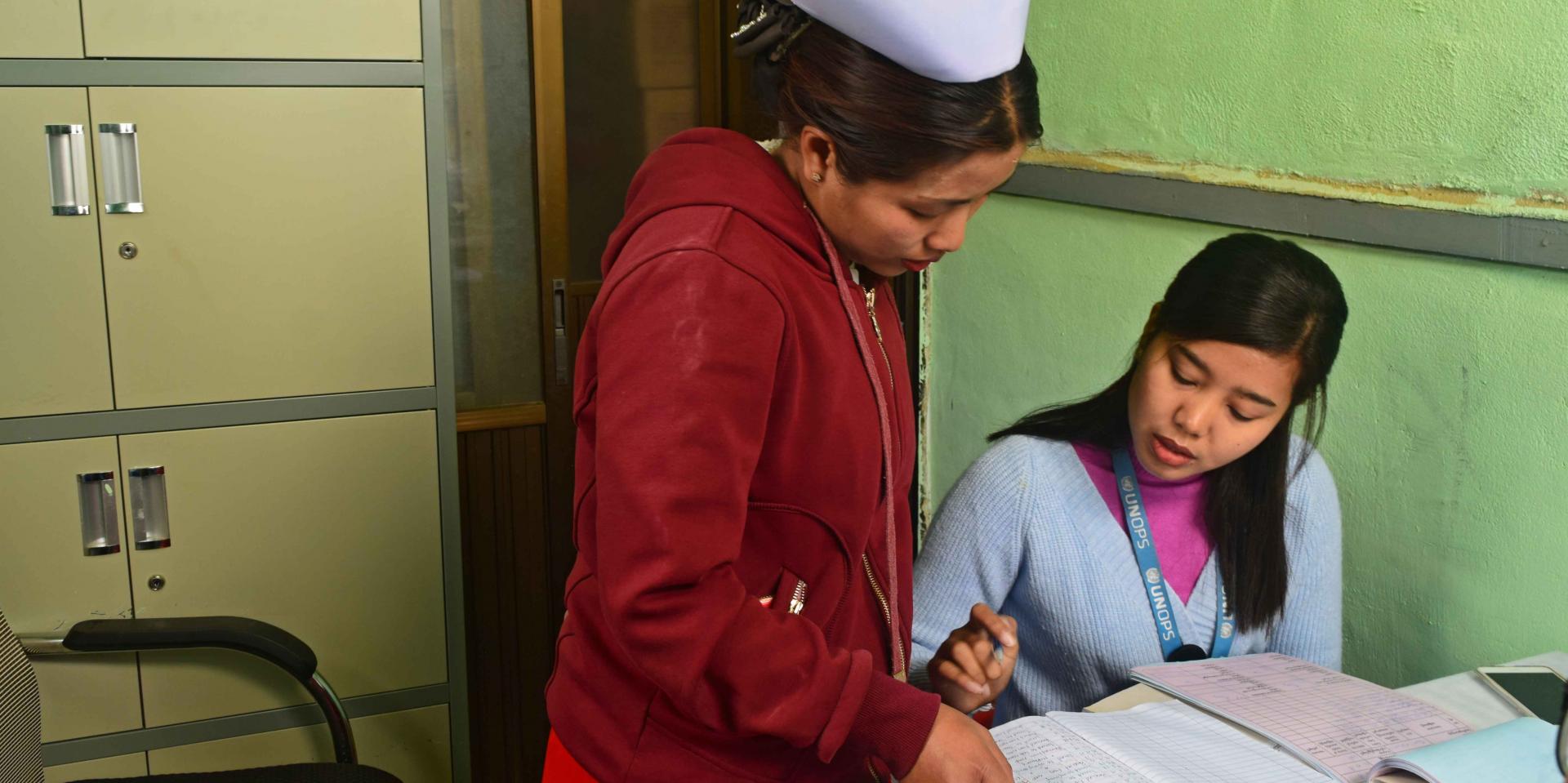 UNOPS-PR logistics team provides on-site logistics support to frontline health posts through regular monitoring visits. In the photo, UNOPS-PR Logistics Assistant Thinzar Aung explains about proper recording and reporting of drug stock to Trained Nurse Daw Kim Hua Hau of Hakha National AIDS Programme. Photo: UNOPS